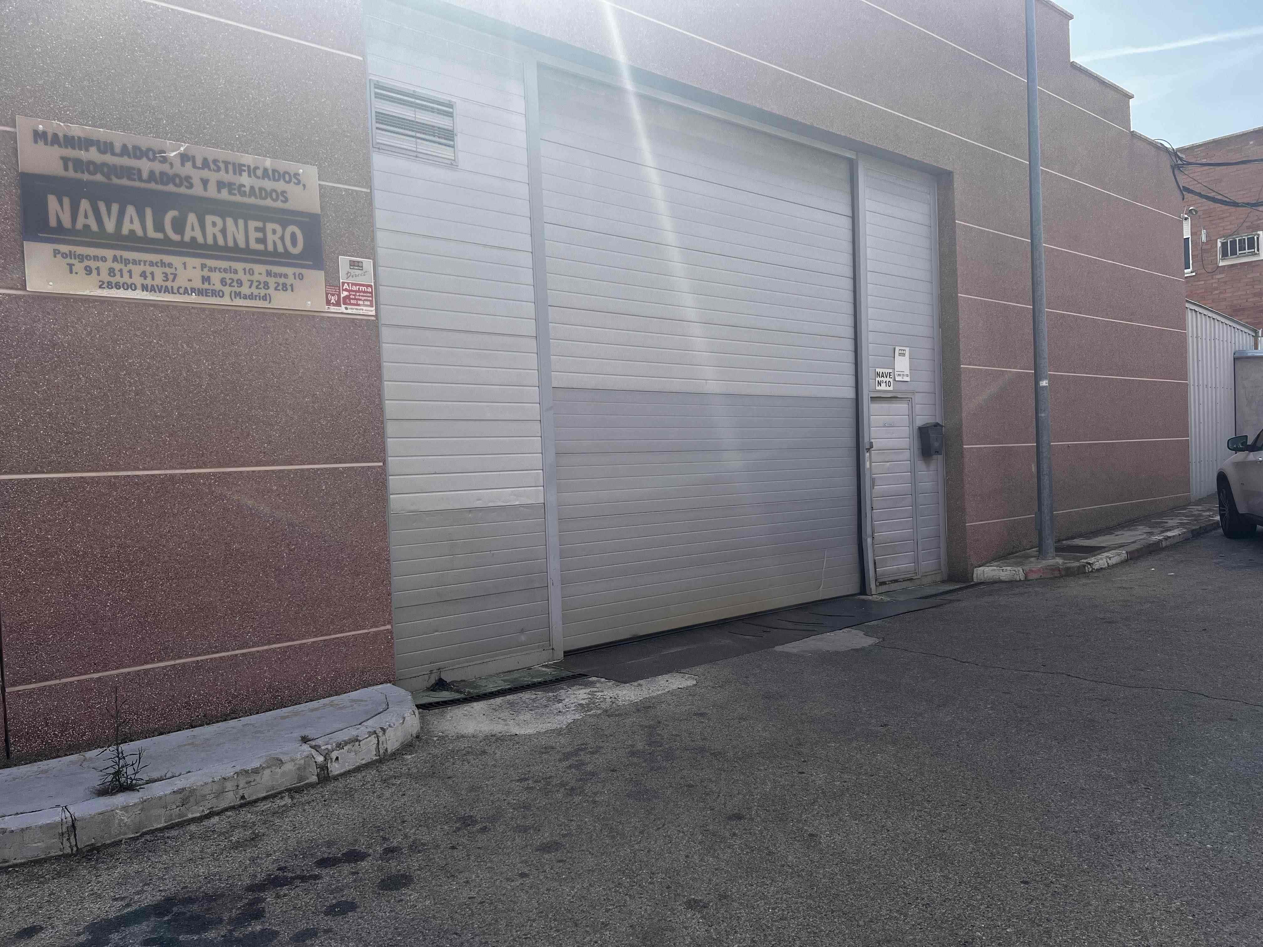 Fachada de nave industrial con puerta de garaje y cartel de Manipulados Navalcarnero